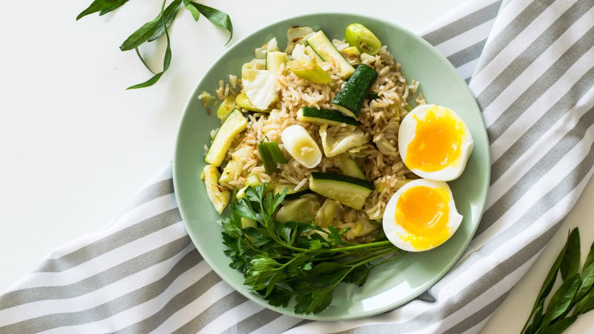 Delicious rice meal with zucchini, greens, and soft-boiled egg, perfect for a healthy diet.